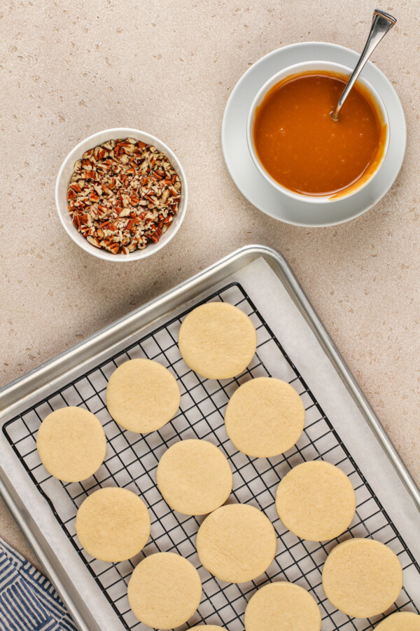 Cooled sugar cookies wait to be topped with caramel and nuts.