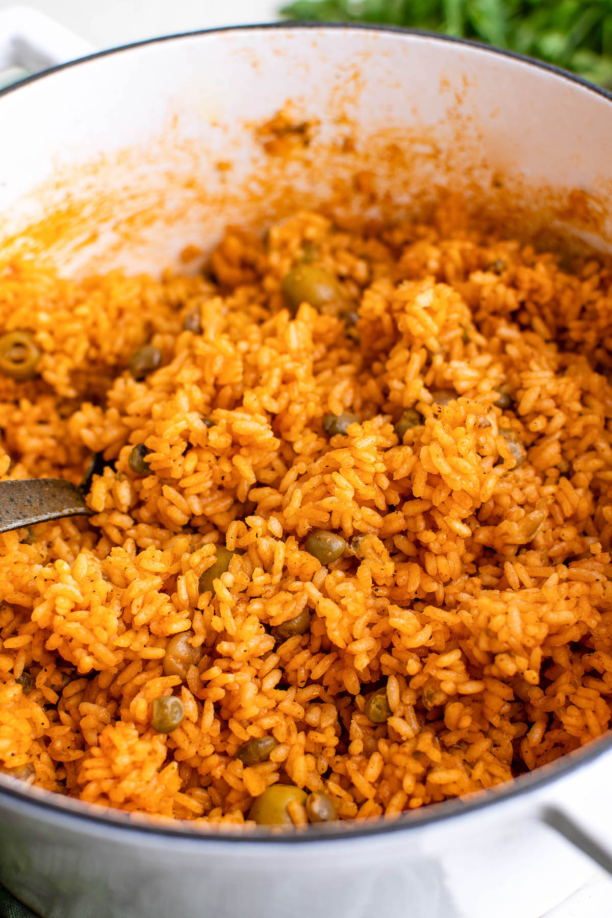 A pot of arroz con gandules with a serving spoon stuck inside it.