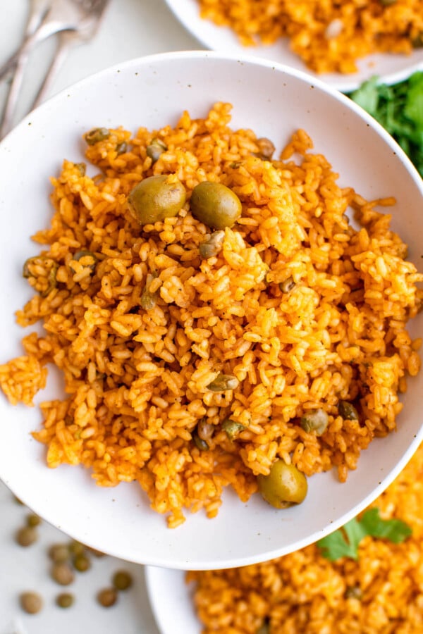 A bowl of yellow Puerto Rican rice with gandules (pigeon peas) and olives.