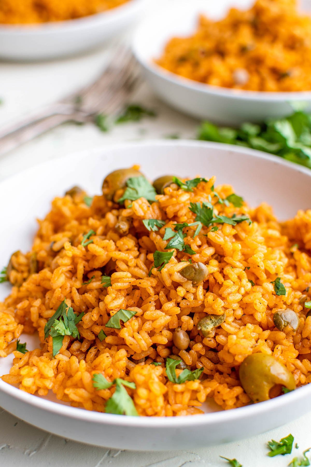 A bowl of arroz con gandules with fresh herbs on top.