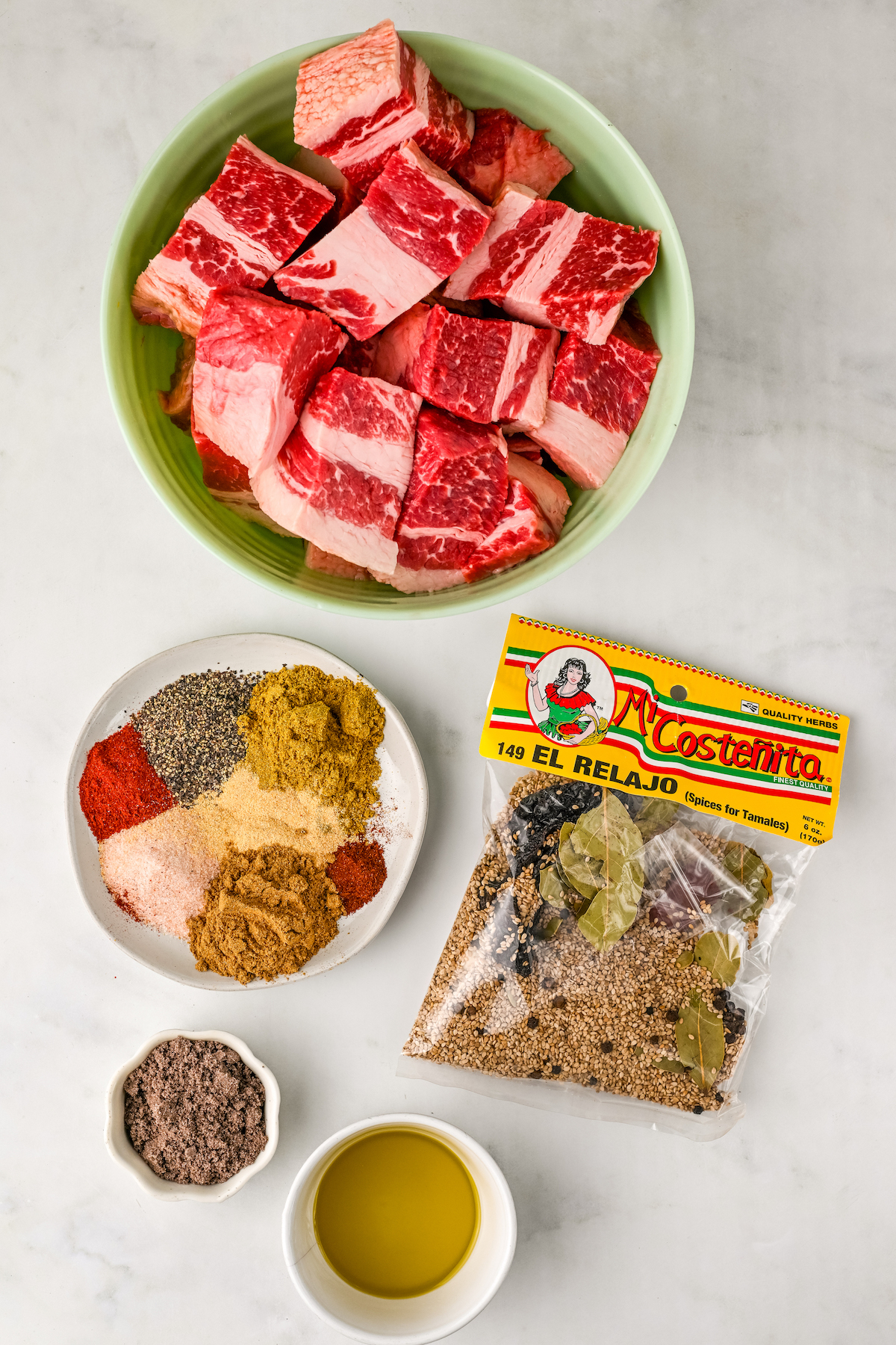 Ingredients for the filling for a beef tamale recipe arranged in bowls on a countertop.