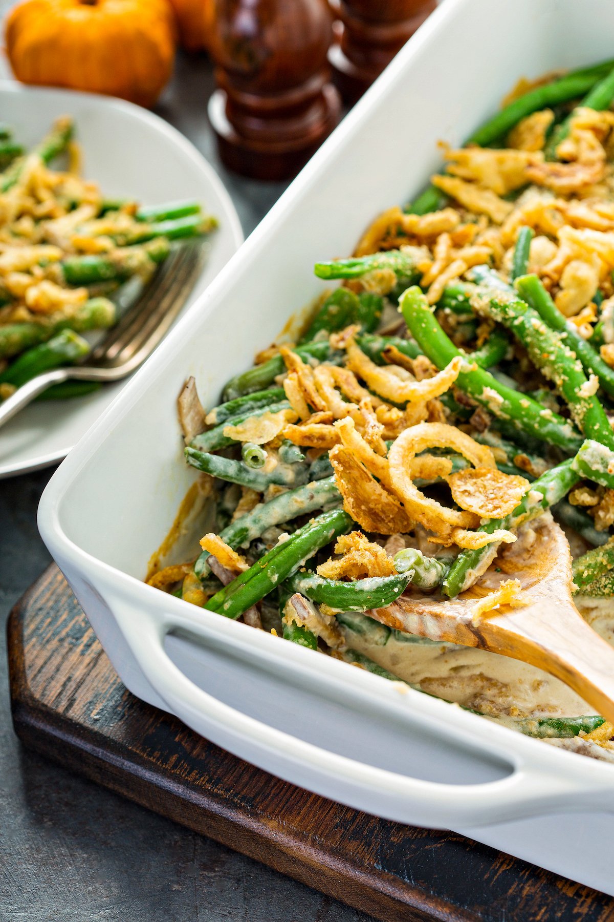 A spoon lifting a serving of the best green bean casserole made from scratch with fresh green beans and a homemade cream of mushroom soup.