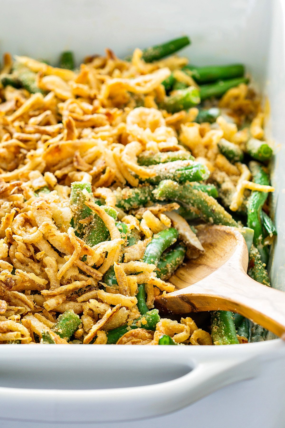 Best green bean casserole from scratch with fresh green beans and crispy fried onions baked in a white baking dish.