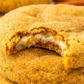 Pumpkin cheesecake cookies with a bite taken out of one.