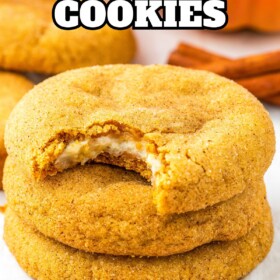 Pumpkin cheesecake cookies stacked on top of each other with a bite taken out of one cookie.