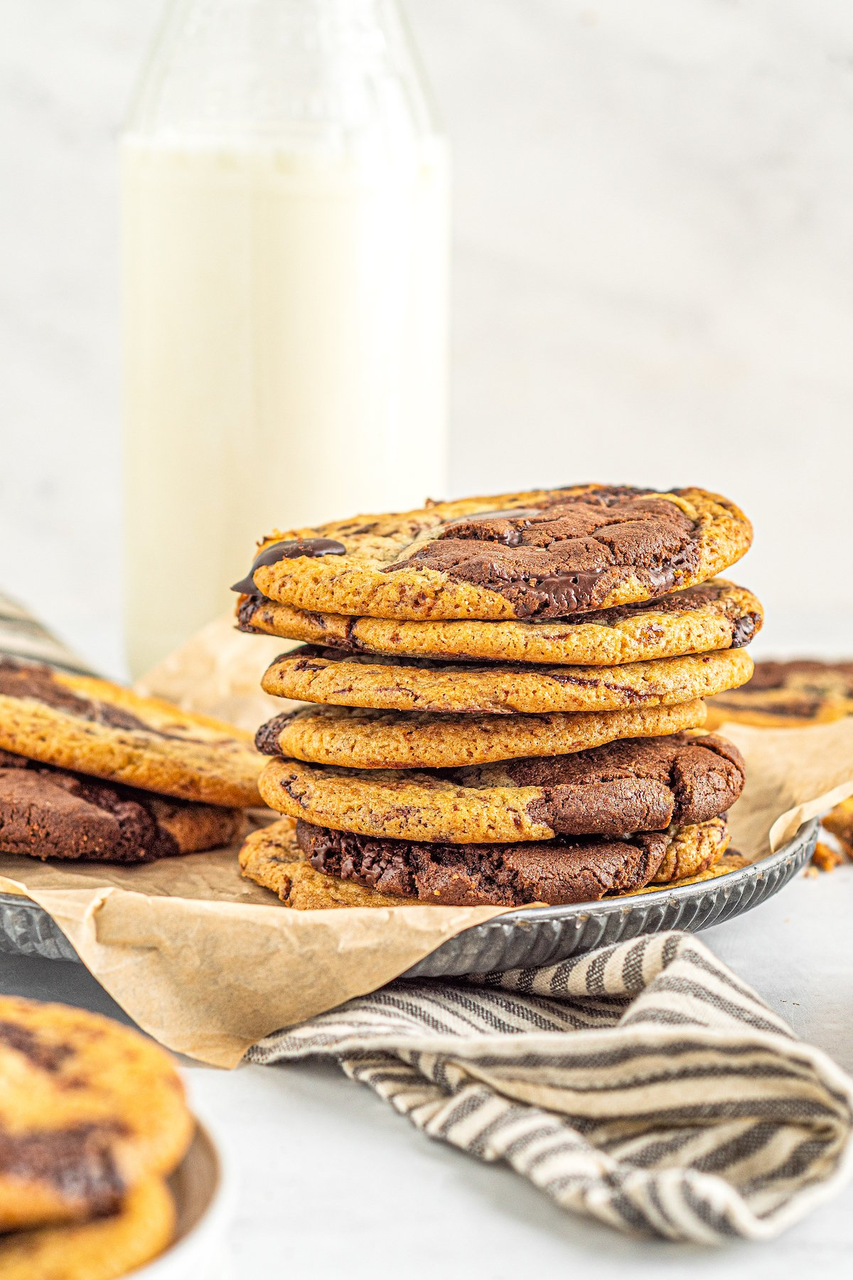 A stack of brookies cookies with a jug of milk in the background. 