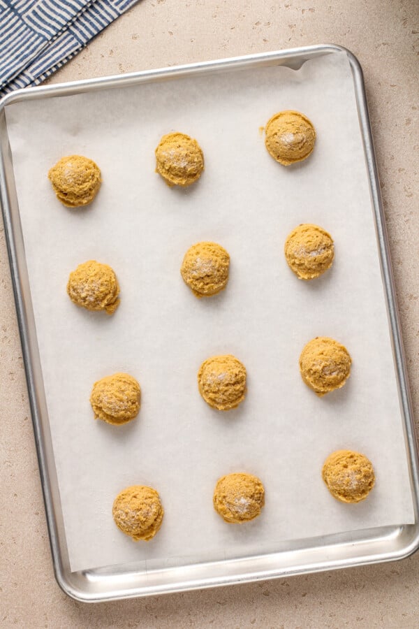 Cookie dough arranged in rows on a cookie sheet lined with parchment paper.