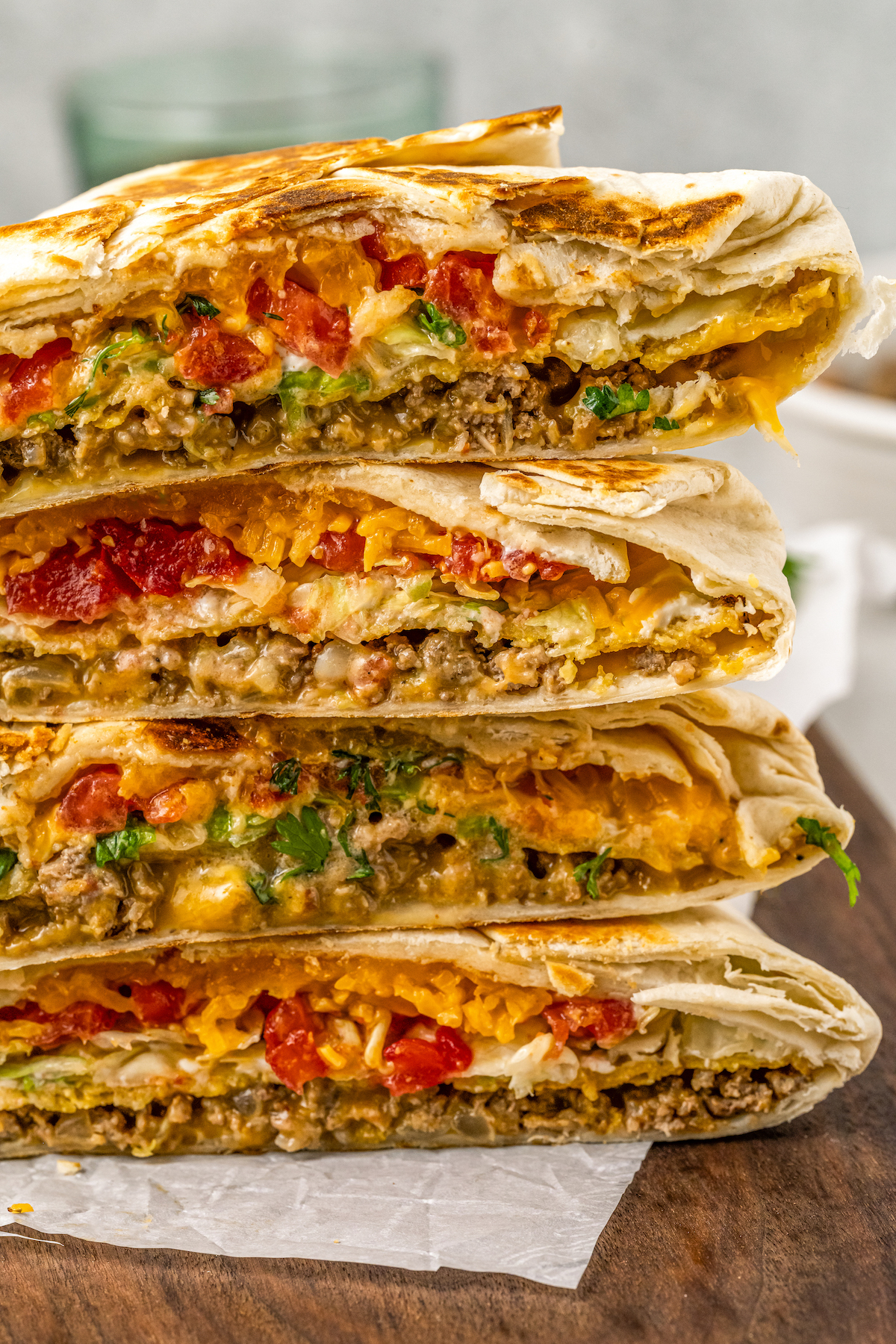 Four crunchwrap supremes cut in half to show the layered insides and then stacked on top of each other.