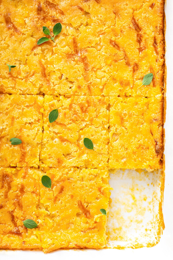 Corn bread casserole in a white baking dish cut into squares.