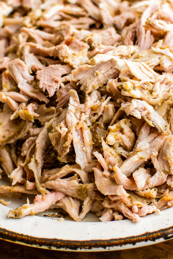 Up close image of juicy shredded Pernil, marinated and roasted pork shoulder, on a plate.