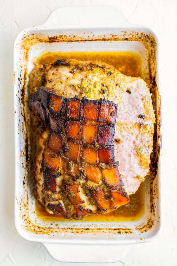 Roasted pernil with crispy skin on top in a baking dish.