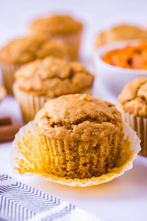 Pumpkin oat muffin with the muffin liner being removed.