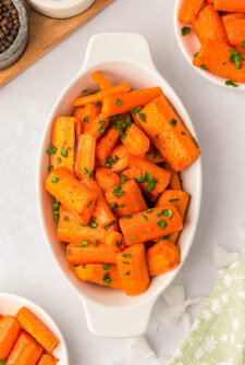 Roasted carrots with honey in a serving bowl topped with fresh parsley.