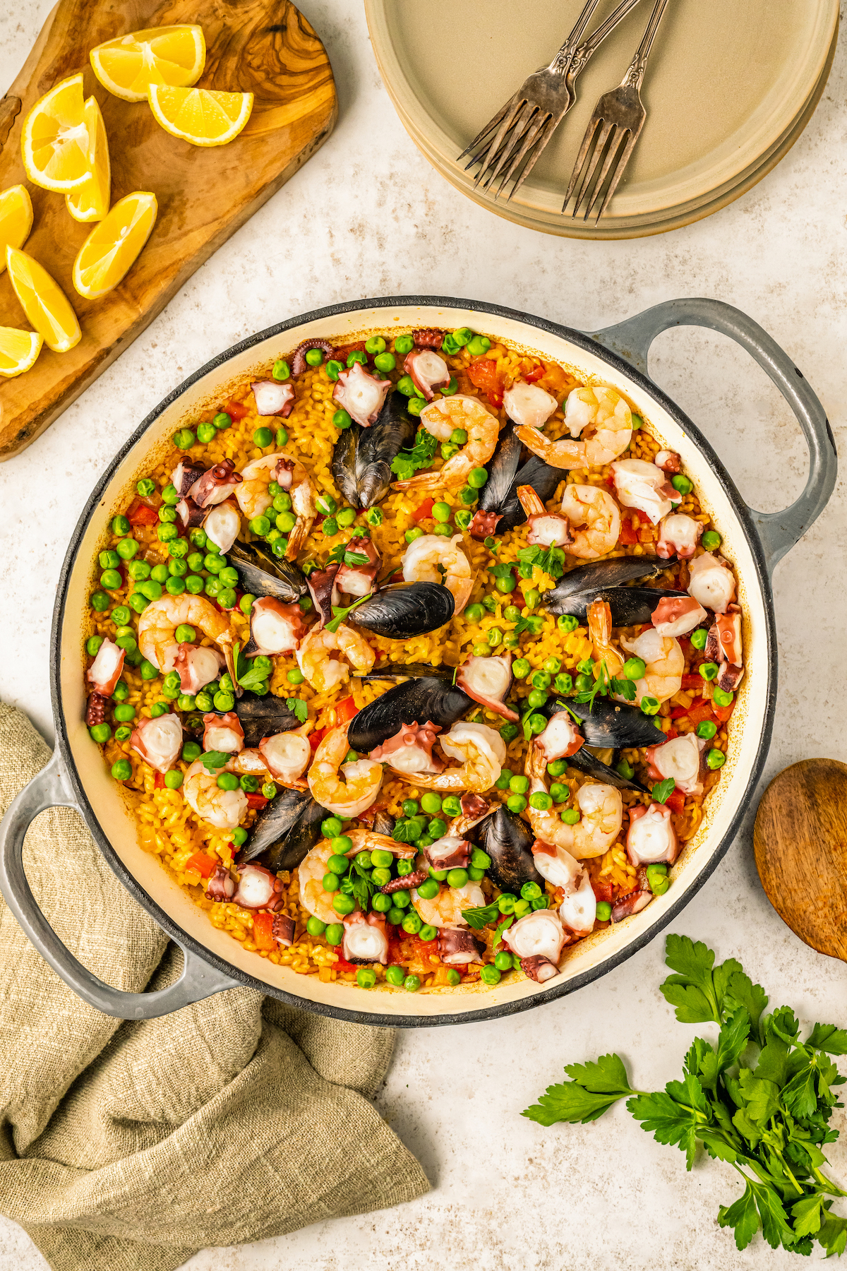 Pan with seafood paella with juicy shrimp, octopus and mussels with lemon wedges on the side. 