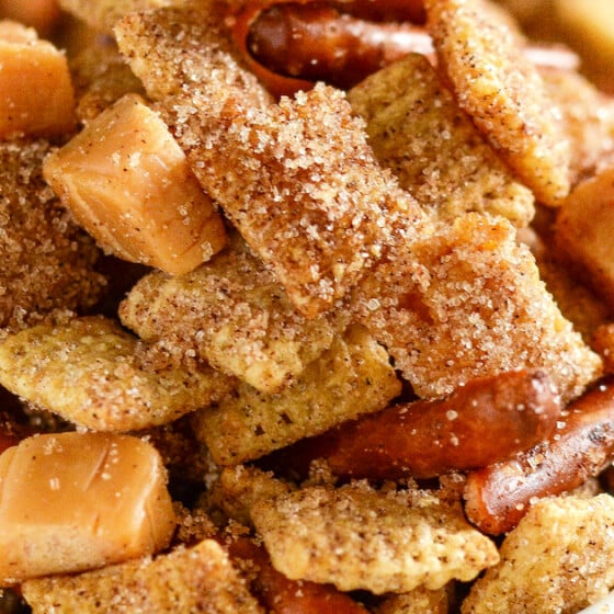 A bowl of Churro Chex mix coated in cinnamon sugar with caramel squares and pretzels.