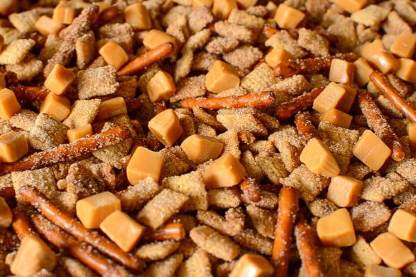 Churro Chex mix on a baking sheet after baking with caramel squares sprinkled on top before mixing.