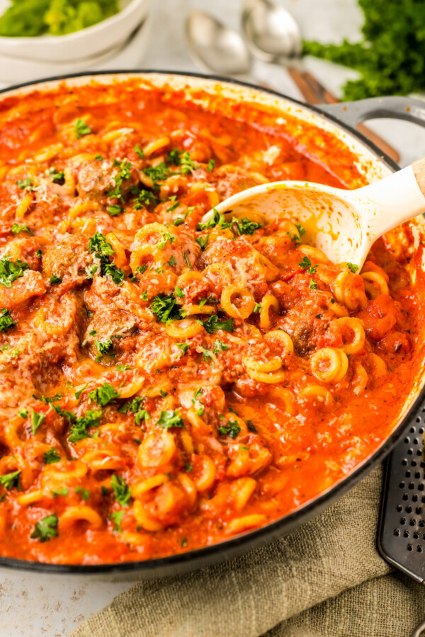 Cooked pasta rings in tomato sauce with meatballs. 