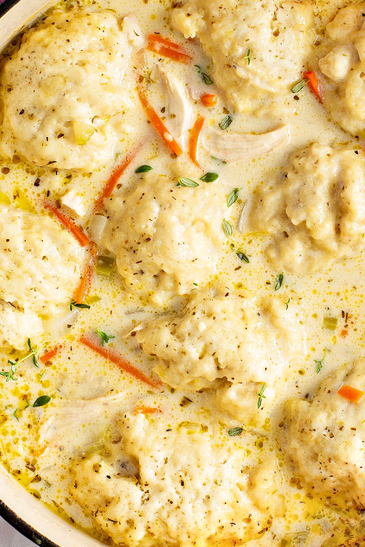 Up close image of fluffy dumplings floating in a pot of creamy chicken and dumplings.