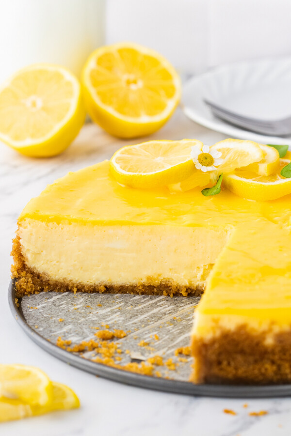 A lemon cheesecake topped with lemon curd with a slice removed.