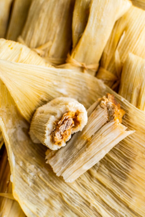 An unwrapped tamale cut in half to show the pork filling.