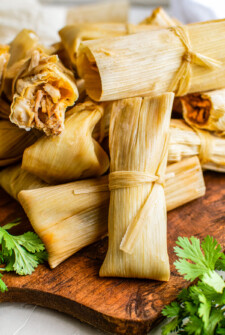 Wrapped tamales in corn husks stacked against each other.