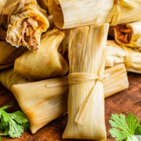 Wrapped tamales in corn husks stacked against each other.
