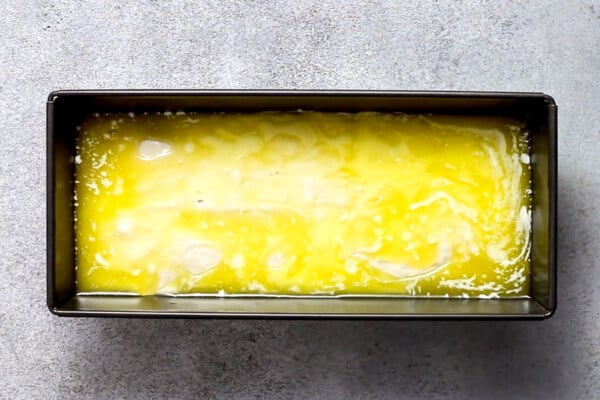 Butter poured over the top of bread batter in a loaf pan.
