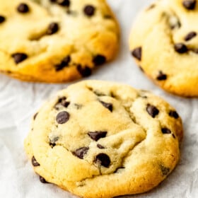 Thick chocolate chip cookies with crisp edges and soft, chewy centers arranged on a cooling rack.