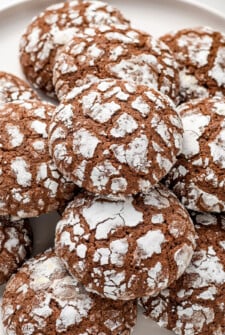 Soft and pillowy homemade chocolate crinkle cookies coated in powdered sugar are stacked on top of each other.