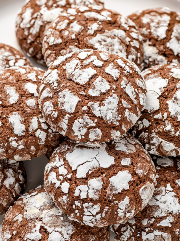 Soft and pillowy homemade chocolate crinkle cookies coated in powdered sugar are stacked on top of each other.