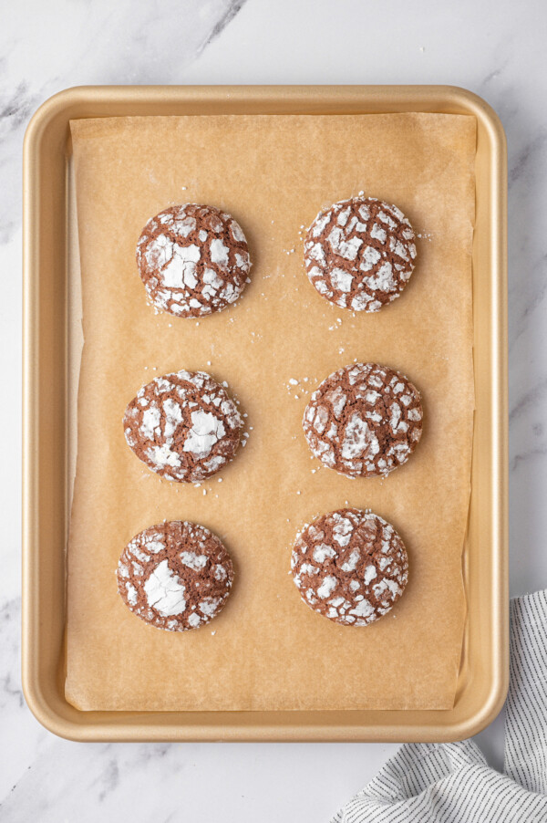 Freshly baked chocolate cookies on a baking sheet lined with parchment paper.