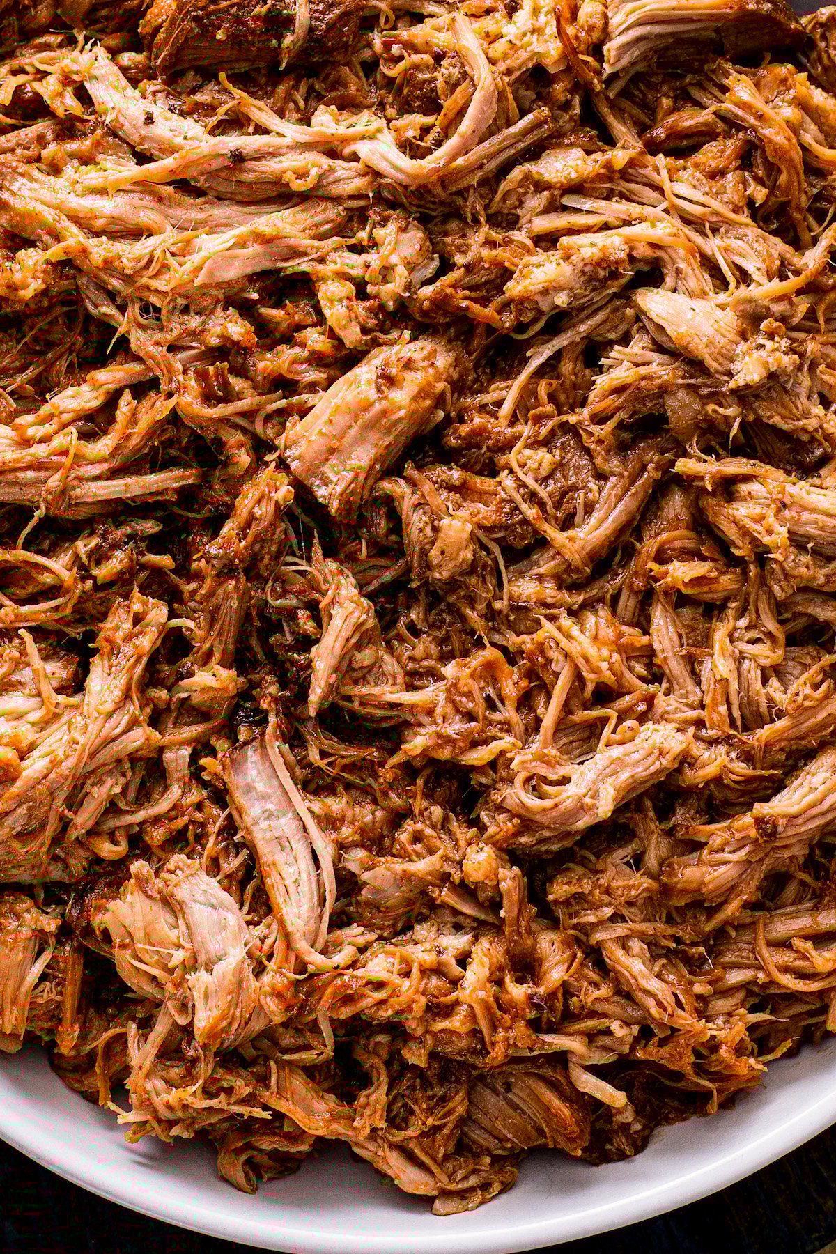 Up close image of slow cooker pulled pork shredded and coated in bbq sauce in a bowl.