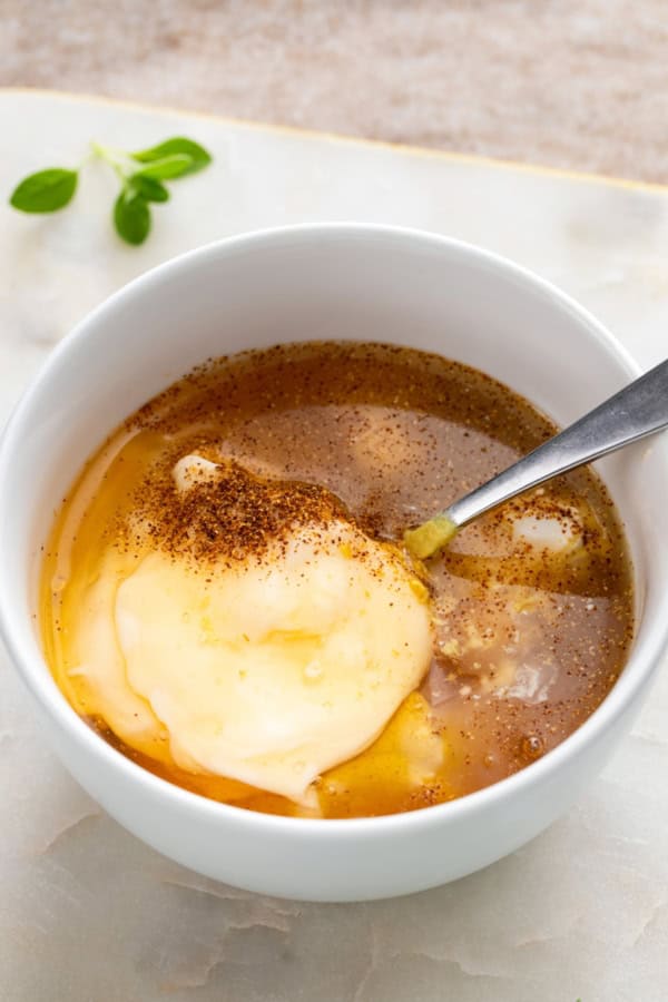 Ingredients are being added to a bowl to make honey mustard.