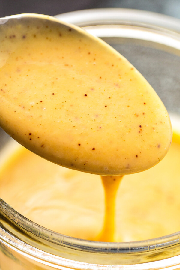 Honey mustard sauce being poured into a jar.