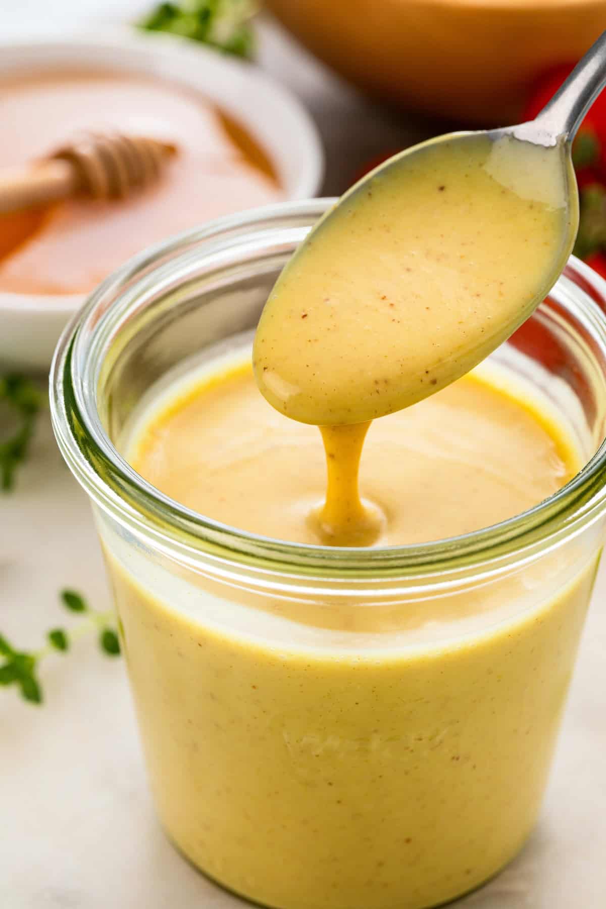 Homemade sweet and spicy mustard with honey is being drizzled with a spoon.