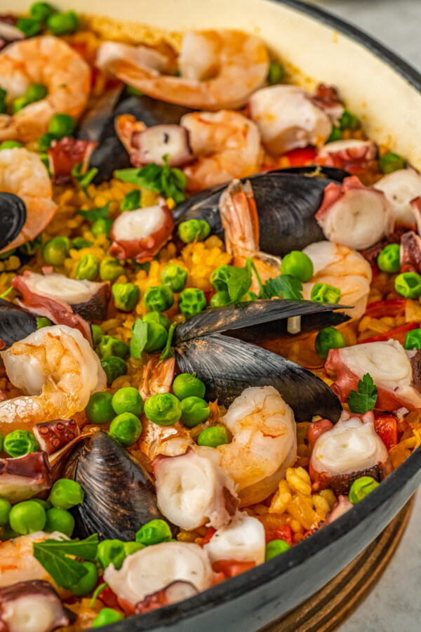Cooked shrimp, mussels and octopus on top of a pan of paella.