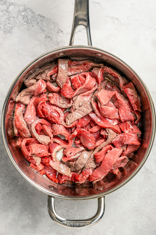 Strips of steak being seared in a skillet.