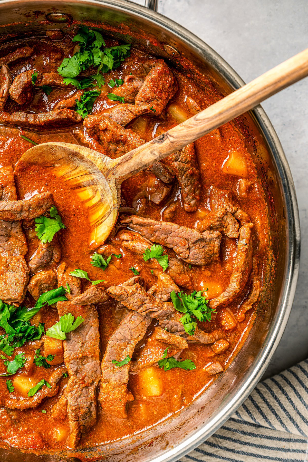 Cooked steak ranchero simmering in a skillet with spicy ranchero sauce and potatoes.