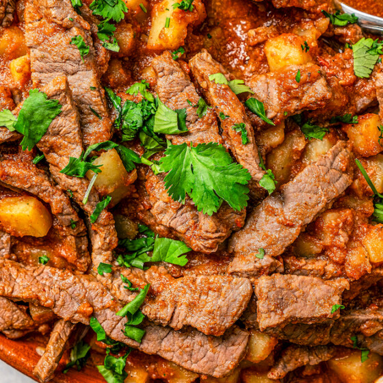 Spicy and tender Bistec Ranchero with potatoes served in a large serving bowl with fresh cilantro on top.