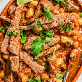 Steak ranchero with potatoes in a spicy tomato sauce on a serving platter.