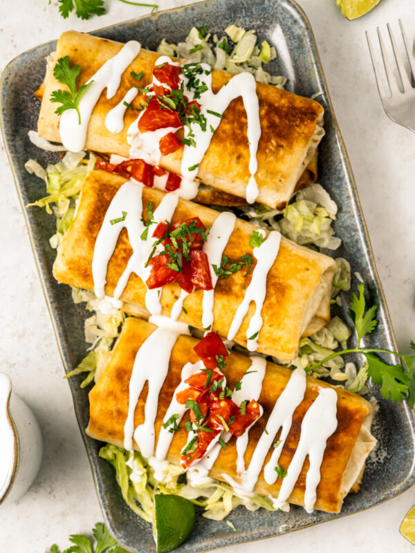 Three chimichangas with pico de gallo, lettuce, and Mexican crema.