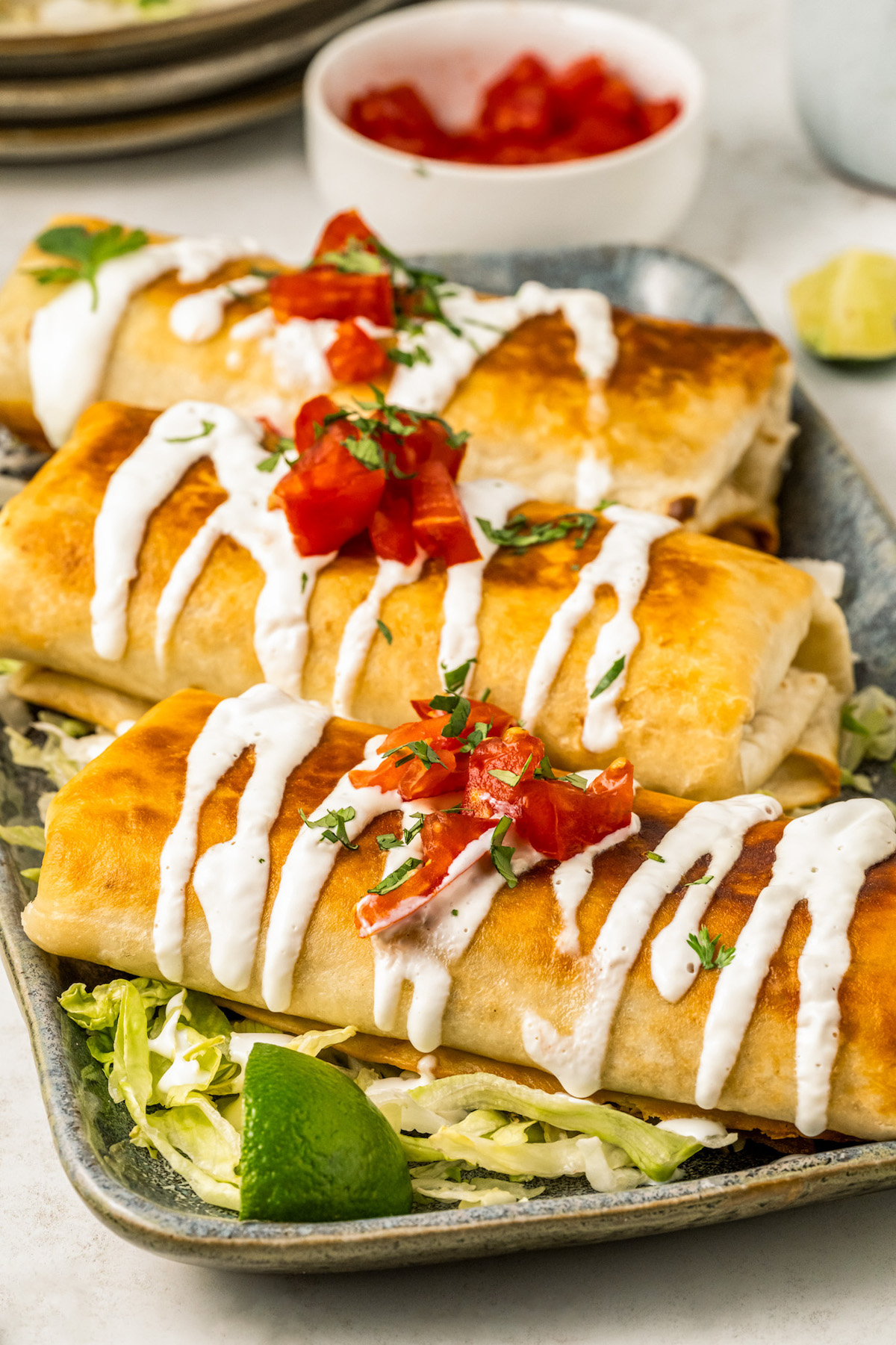 Three crispy, golden brown chimichangas topped with with pico de gallo and Mexican crema. 
