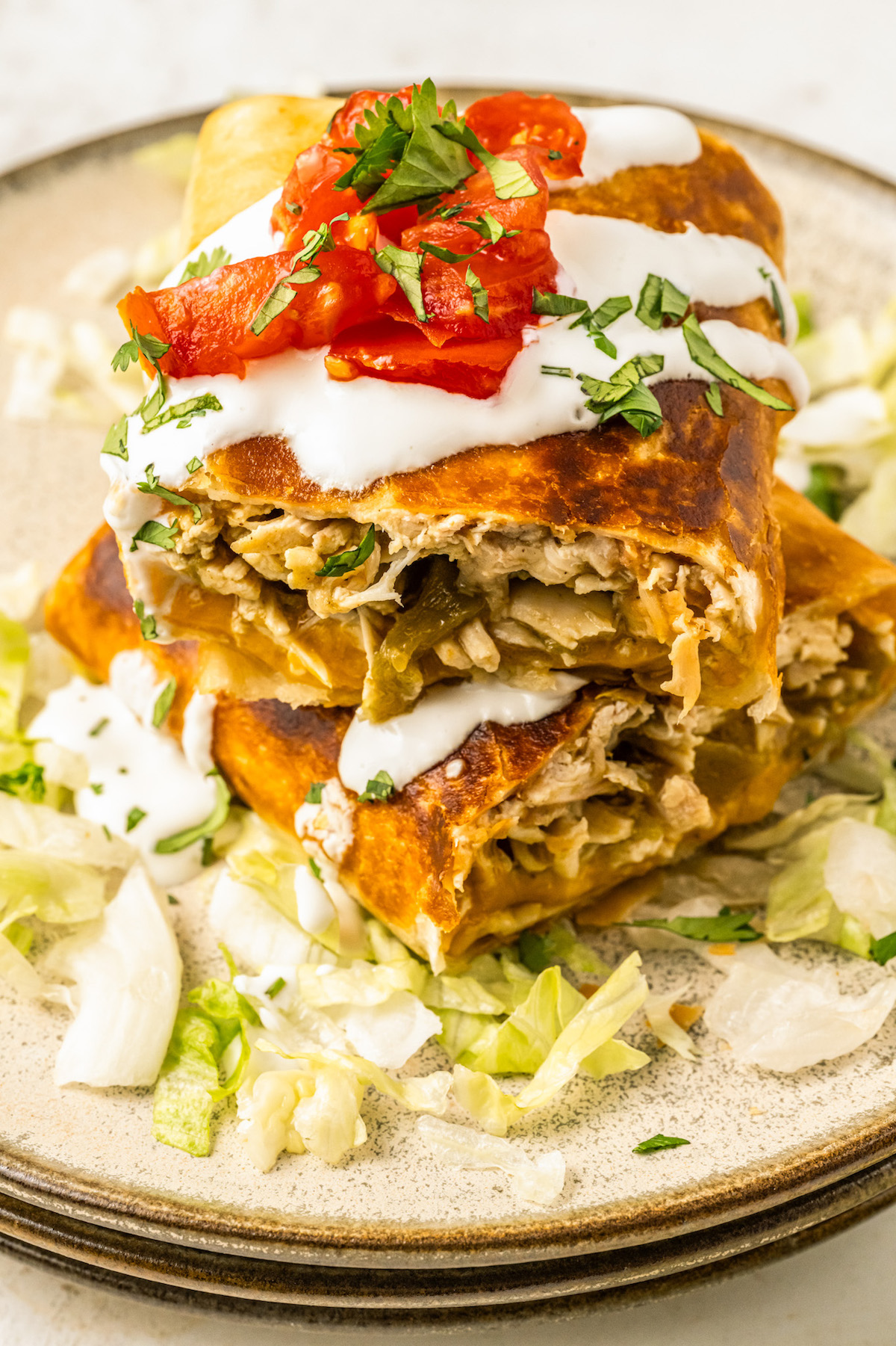 Sliced chimichanga halves with spicy chicken filling and toppings stacked on top of each other.