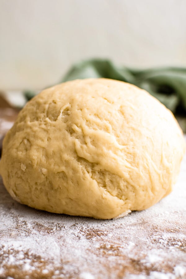 Empanada dough ball on a cutting board dusted with flour.