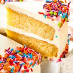 A slice of homemade vanilla cake being lifted with a serving spatula.