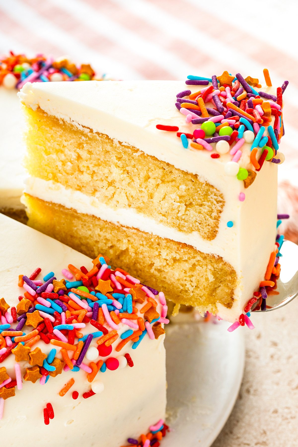 A slice of homemade vanilla cake being lifted with a serving spatula.