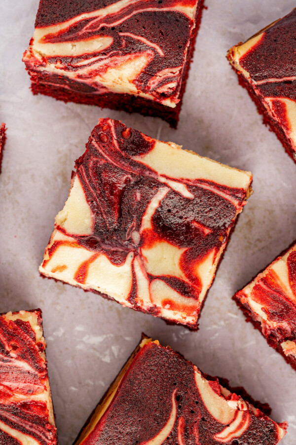 Rich and fudgy red velvet brownies swirled with cream cheese, baked and cut into squares.