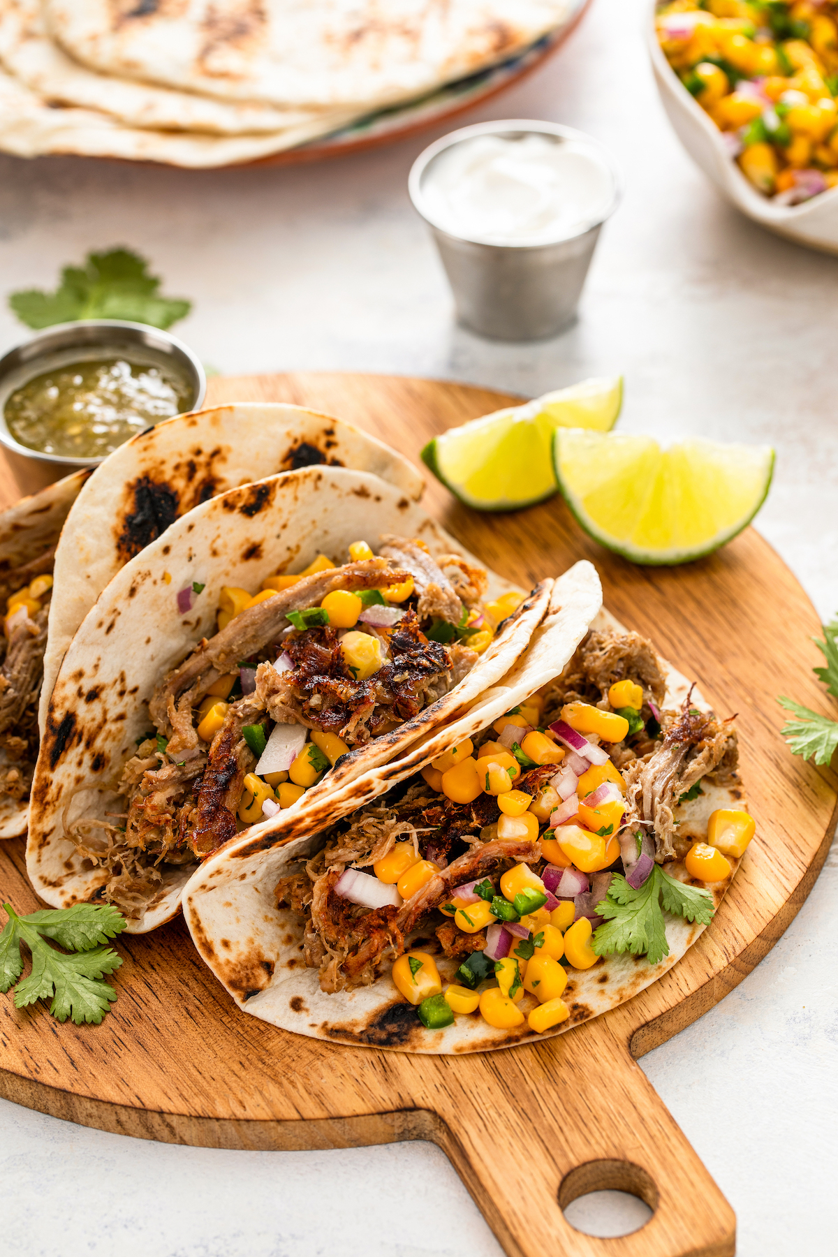 Juicy and crispy crock pot carnitas served in flour tortillas and topped with fresh corn salsa.