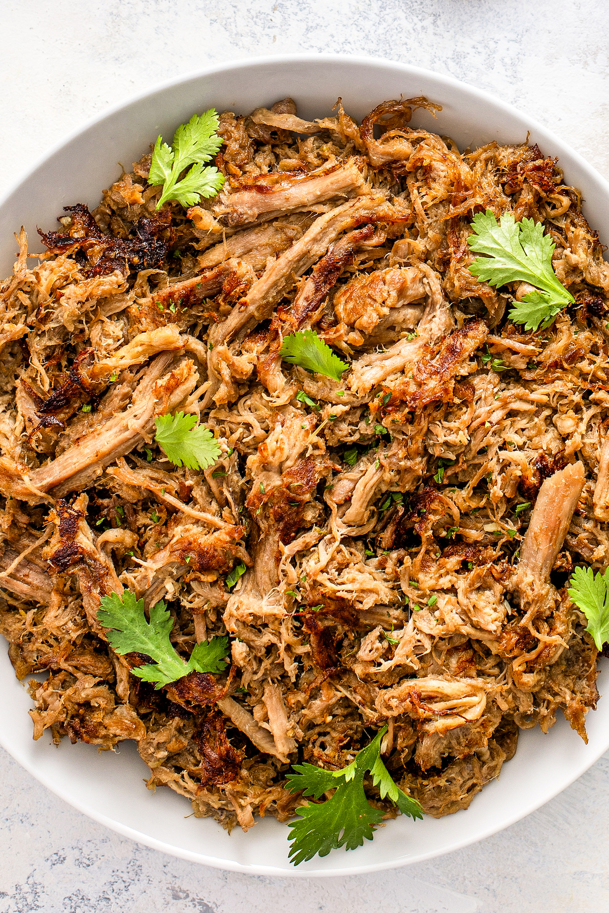 Juicy and tender shredded crock pot carnitas placed in a serving bowl.
