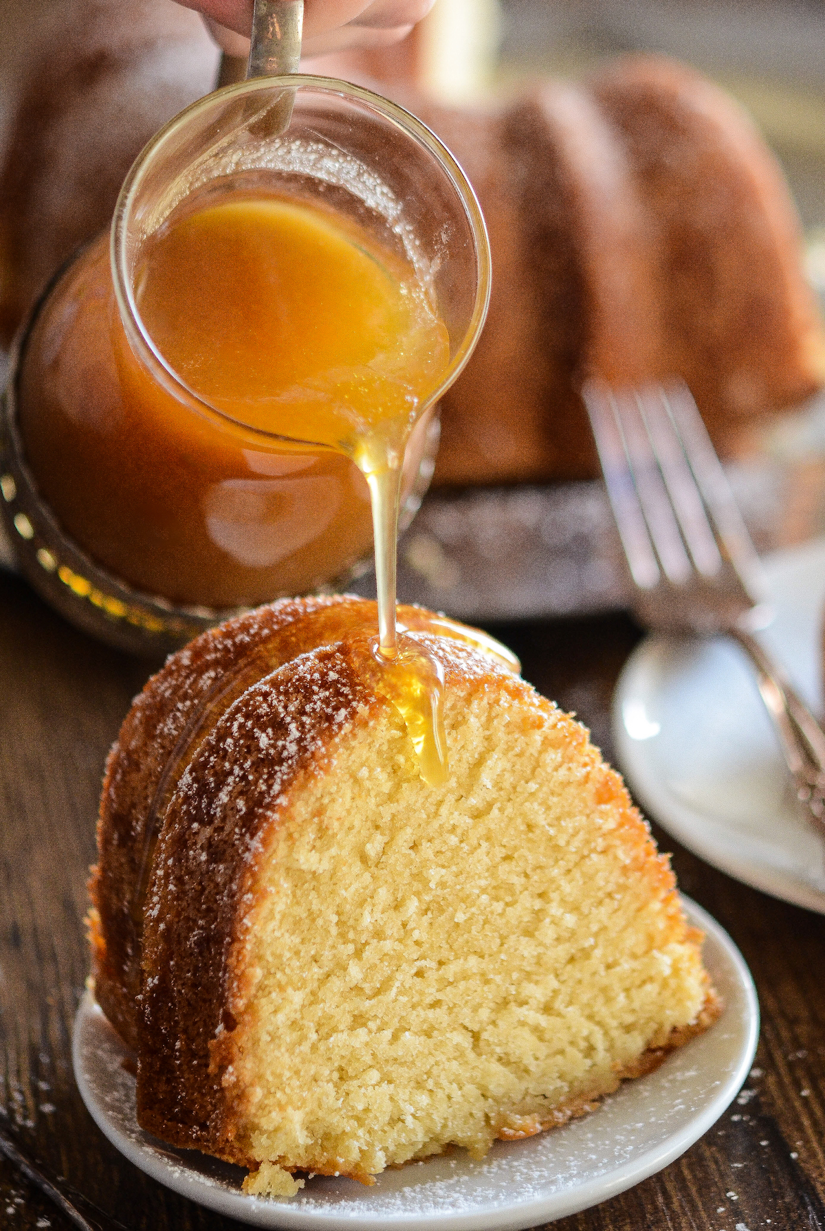 Sweet and dense almond pound cake with a warm brown sugar amaretto sauce being poured on top.